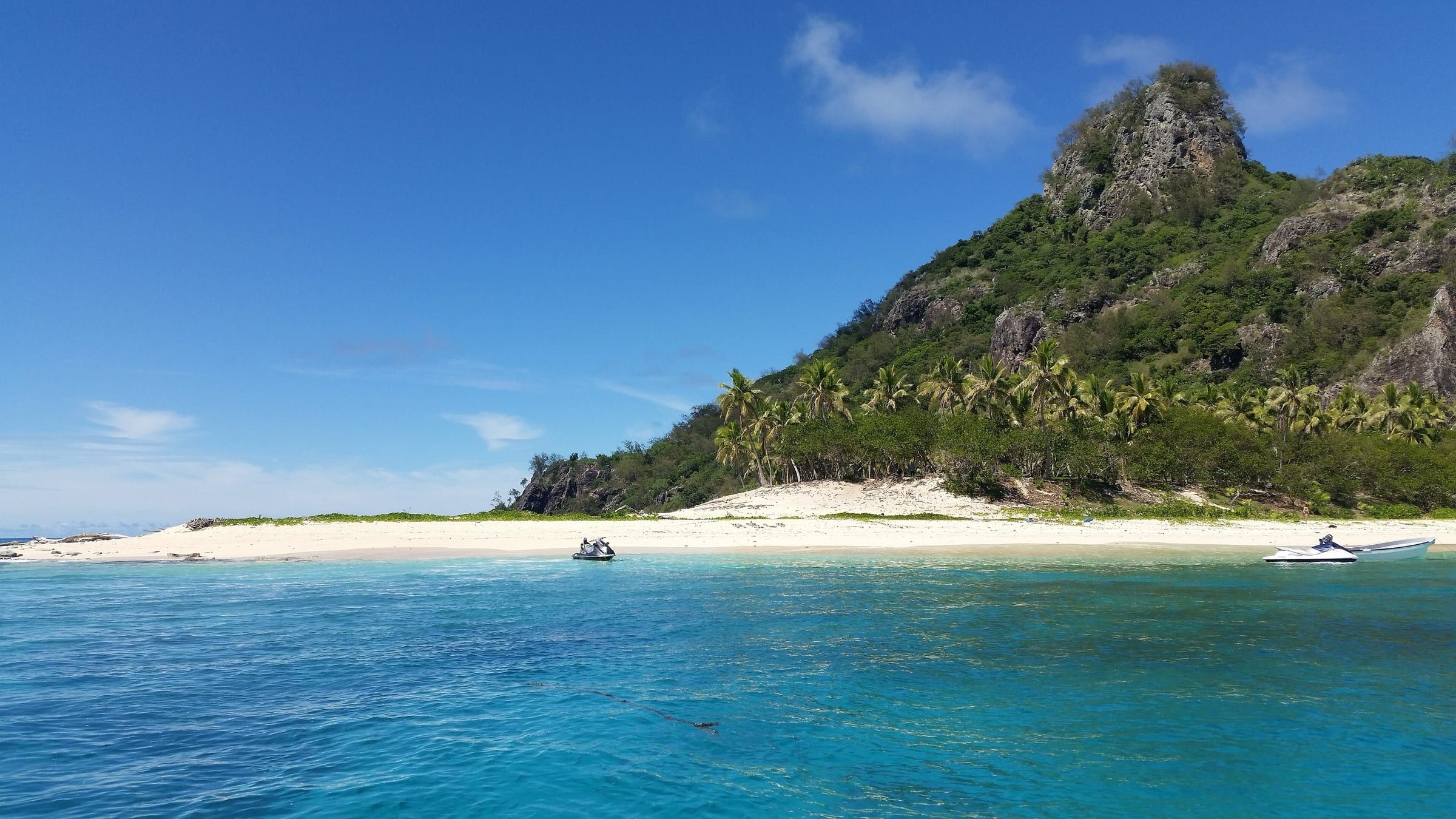 Jet skis pulled up off the white-sand beach of Monuriki, an uninhabited Mamanuca island with a rocky, palm-covered peak.